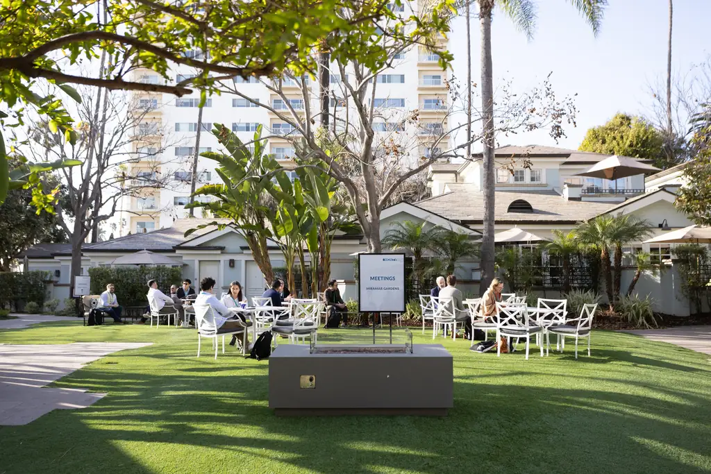 Guests meeting at tables on the bungalow lawn in the sun
